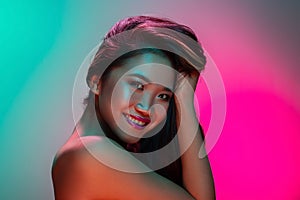 High Fashion model woman in colorful bright lights posing in studio