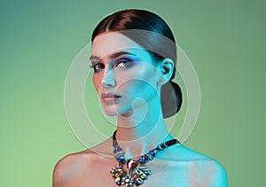 High Fashion model woman in colorful bright lights posing in studio.