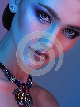 High Fashion model woman in colorful bright lights posing in studio.