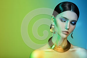 High Fashion model woman in colorful bright lights posing in studio.