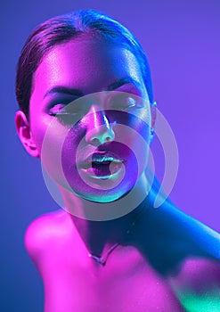 High Fashion model woman in colorful bright neon lights posing in studio, night club. Portrait of beautiful girl in UV