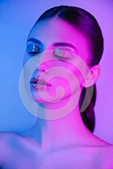 High Fashion woman in colorful bright neon uv blue and purple lights, posing in studio