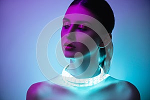High Fashion woman in colorful bright neon uv blue and purple lights, posing in studio