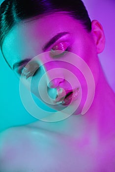 High Fashion woman in colorful bright neon uv blue and purple lights, posing in studio