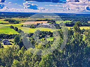 High hilly shores. Oppdal mountain valley landscape background. Sunny day in early summer. View to forest, field and meadows in