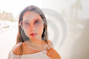 High key portrait of young beautiful and attractive Asian Korean woman wearing cool sunglasses posing outdoors on a sunny day in