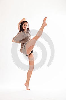 High kick dance by happy young woman in studio