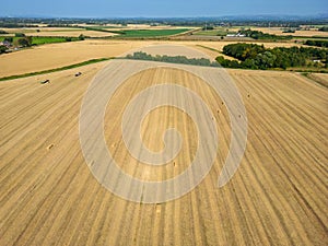 High level aspect view over a wheat field with bales of straw ready for collection in the English countryside