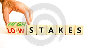 High or low stakes symbol. Concept words High stakes and Low stakes on wooden cubes. Businessman hand. Beautiful white table white