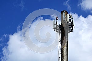 High metal chimney of industrial plant with ladder in the form of metal braces against the background of a cloudy blue sk