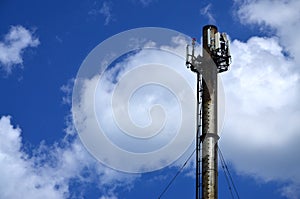 High metal chimney of industrial plant with ladder in the form of metal braces against the background of a cloudy blue sk