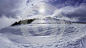 High mountain snowy landscape with sun rays and sky with clouds. La Morcuera