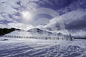 High mountain snowy landscape with sun rays and sky with clouds. La Morcuera