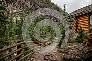 High mountain village - a stone path, a wooden fence in forest and the slopes of the Rocky Mountains. dramatic tone