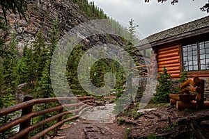 High mountain village - a stone path, a wooden fence in the middle of a coniferous forest and the slopes of the Rocky Mountains.