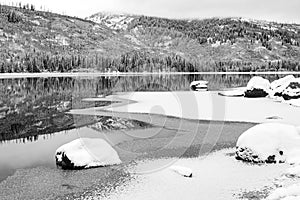 High mountain wilderness winter lake with forest reflection