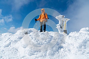 High mountaineer dressed bright orange softshell jacket on the snowy mountain summit.  Active people concept image on Velky