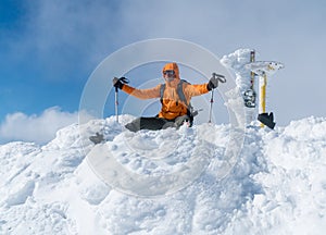 High mountaineer dressed bright orange softshell jacket on the snowy mountain summit.  Active people concept image on Velky