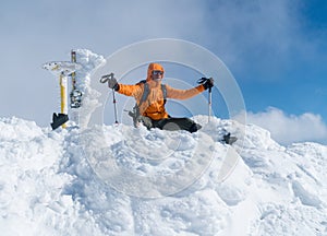 High mountaineer dressed bright orange softshell jacket on the snowy mountain summit.  Active people concept image on Velky