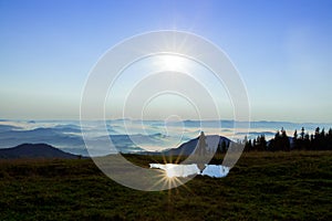 High in the mountains above the clouds a young man is looking for a cellular connection holding his phone high