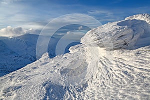 High mountains and blue sky. Mysterious fantastic rocks frozen with ice and snow of strange fairytales forms and structures.