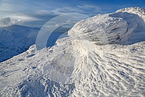 High mountains and blue sky. Mysterious fantastic rocks frozen with ice and snow of strange fairytales forms and structures.