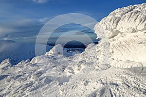 High mountains and blue sky. Mysterious fantastic rocks frozen with ice and snow of strange fairytales forms and structures.