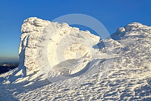 High mountains and blue sky. Mysterious fantastic rocks frozen with ice and snow of strange fairytales forms and structures.