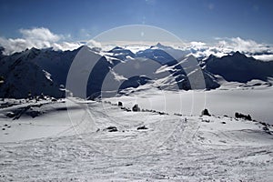 High mountains off-piste slopes for freeride with traces of skis and snowboards, sunny winter day, Caucasus Mountains, Elbrus