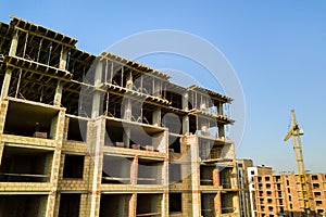 High multi storey residential apartment building under construction. Concrete and brick framing of high rise housing. Real estate