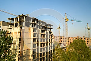 High multi storey residential apartment buildings under construction. Concrete and brick framing of high rise housing. Real estate