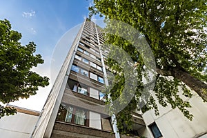 High multistoried apartment building with trees against blue sky