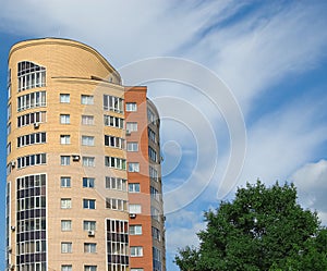 High multistory house, clouds and tree