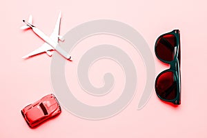High plane toy in airplane travel concept. White aircraft, sunglasses and car on bright pink backdrop in top view