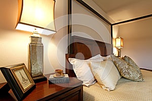 High posts bed with a beautiful beige bedding and nightstand. Cl