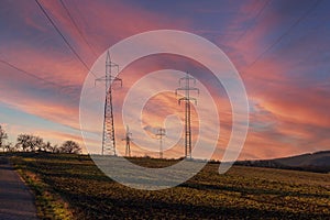 High power poles in the countryside. Colorful sky at sunset