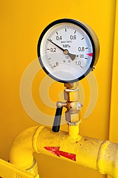 High pressure gauge meter or manometer installed to gas tube in yellow cabinet on industrial plant