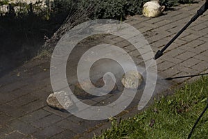 High-pressure washer cleans cobblestones close up in garden of country house
