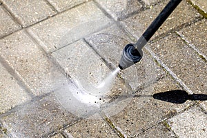 High-pressure washer cleans concrete stones of garden line in country house