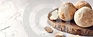 High price white truffles on chopped wood plate closeup. Aromatic condiment mushrooms on rough textured table