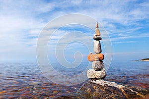 High pyramid of multicolored pebbles on a background of the summer sea.