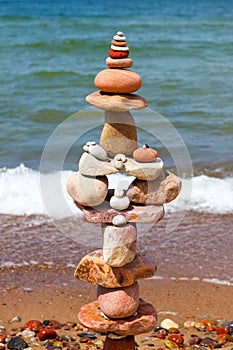 High pyramid of multicolored pebbles on a background of the summer sea