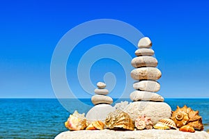 High pyramid of white stones and seashells. Rock Zen in the background of the summer sea.