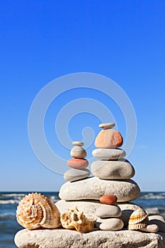 High pyramid of white stones and seashells. Rock Zen in the background of the summer sea