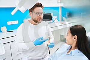 High-qualified stomatologist explaining build of tooth on 3d model