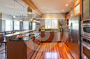 High quality contemporary home kitchen with wood cabinets, hardwood floor, stainless steel appliances, windows and accent lighting photo