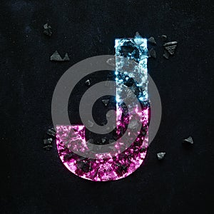 High quality photo of neon colored capital letter on a black textured background.