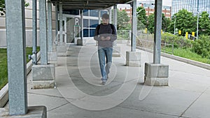 High quality picture of a young men who is walking outside on the street to to from parking lot on the train station.