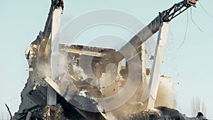 High reach machine trashing destroyed construction by demolition tool, upheaval