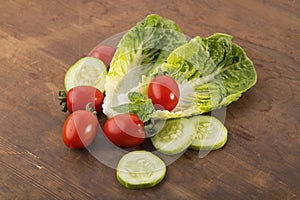 Vegetable: Fresh Green Romaine Lettuce with Baby Tomatoes, Mint Leaves and Cucumber Slices on Brown Wooden Background